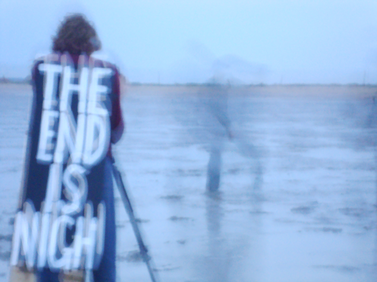 A blurred picture of a person wearing a sandwich board reading "The End Is Nigh"