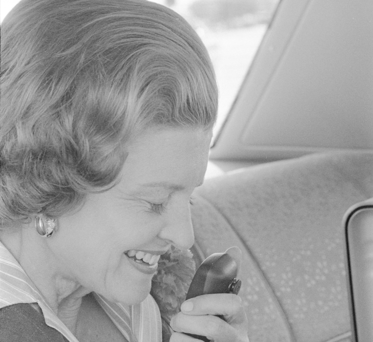 Betty Ford speaking into a CB radio microphone from the backseat of a car