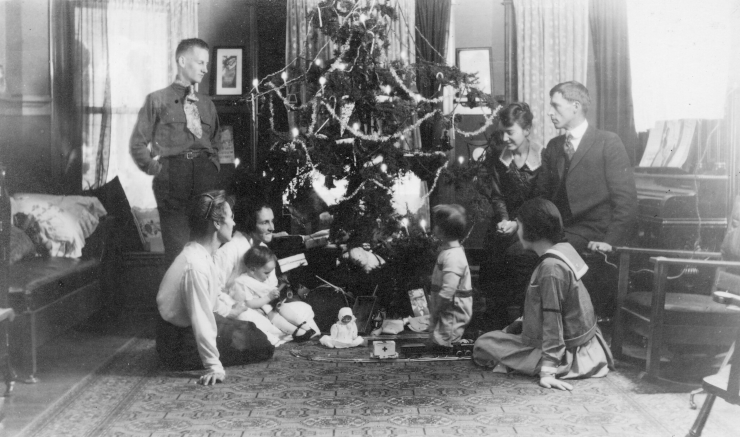 A black-and-white photograph of a family gathered around a decorated Christmas tree