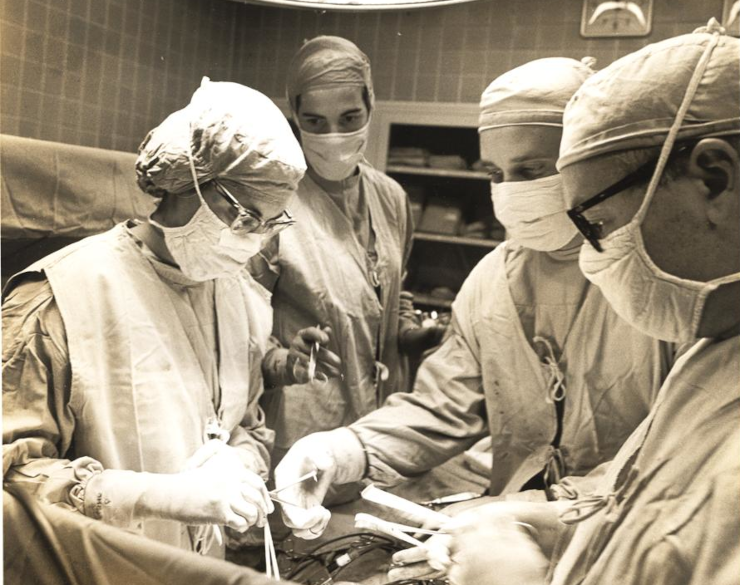 Doctors operating, presumably on a patient, circa 1965