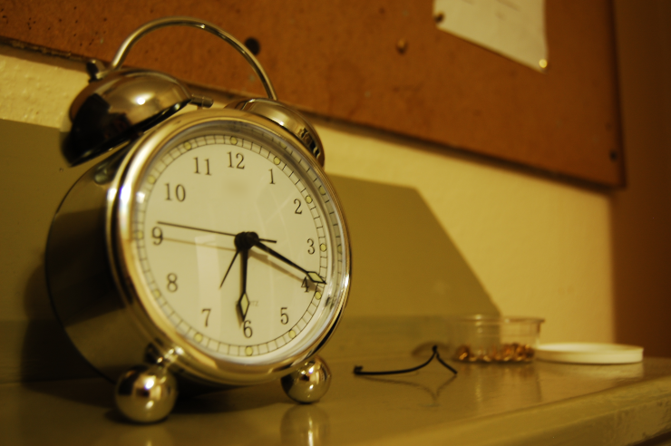 An analog alarm clock on an end table