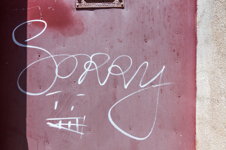 The word "sorry" scrawled on a red metal door