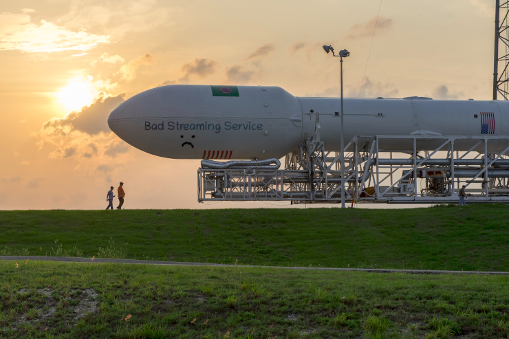 A photograph of the Falcon-9 rocket rolling out, where someone has vandalized it with the phrase Bad Streaming Service and a frowning face, along the forward capsule