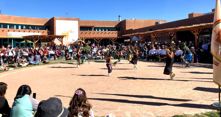 A celebration of Indigenous Peoples' Day, including people in a circle, watching a dance