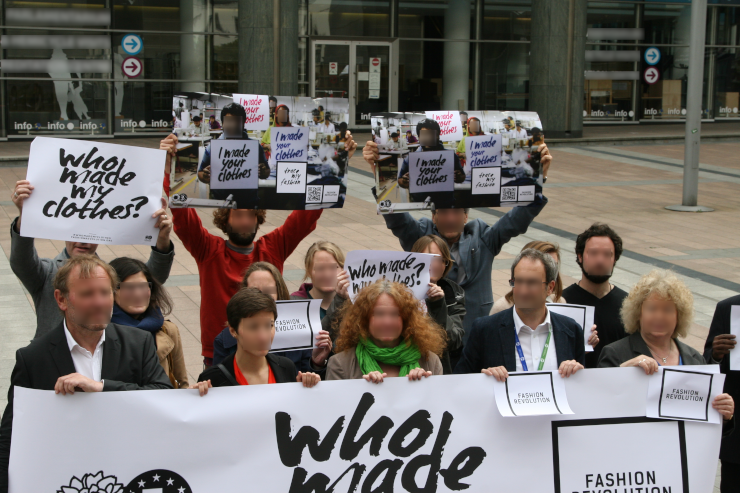 Photograph displaying a diverse-looking group of people protesting fast fashion with Fashion Revolution's slogan of "Who Made My Clothes?"