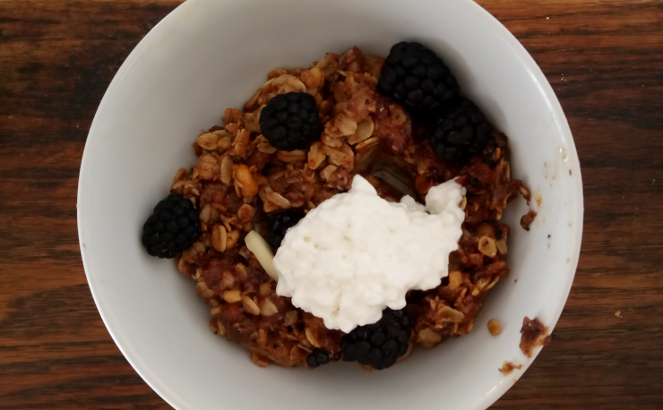 A bowl of toasted oats, walnuts, banana, blackberries, and cottage cheese