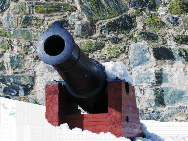 A cannon outside a stone wall, partly covered in snow