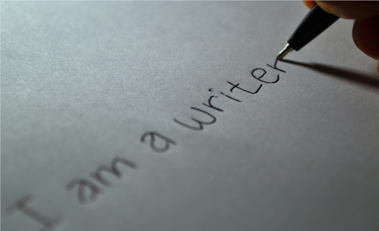 A pen writing the phrase "I am a writer" on plain paper
